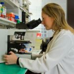 woman in white coat holding black dslr camera