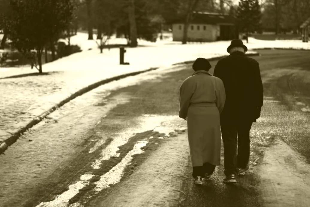 Elderly couple on a winter road holding hands
