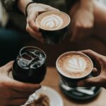three person holding coffee mug and glass with soda inside