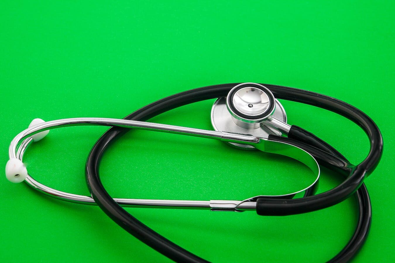 Stethoscope placed on a vibrant green background, symbolizing healthcare and medical practice.