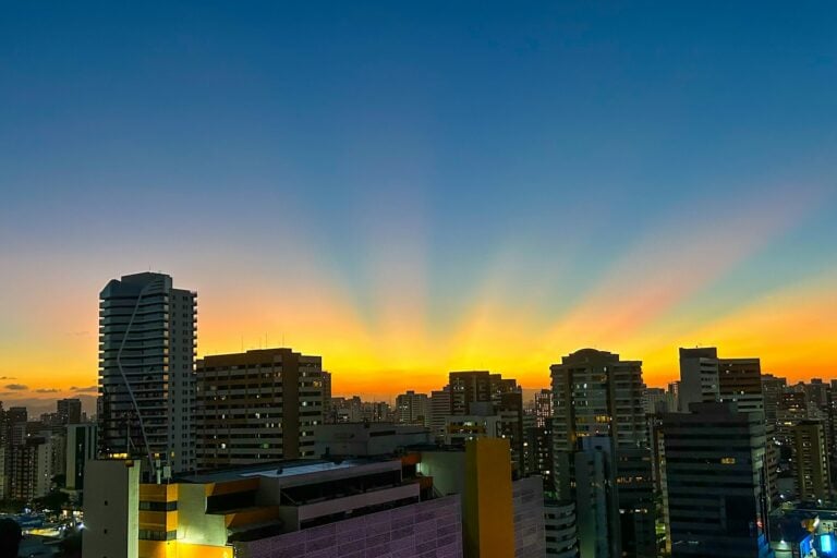the sun is setting over a city with tall buildings