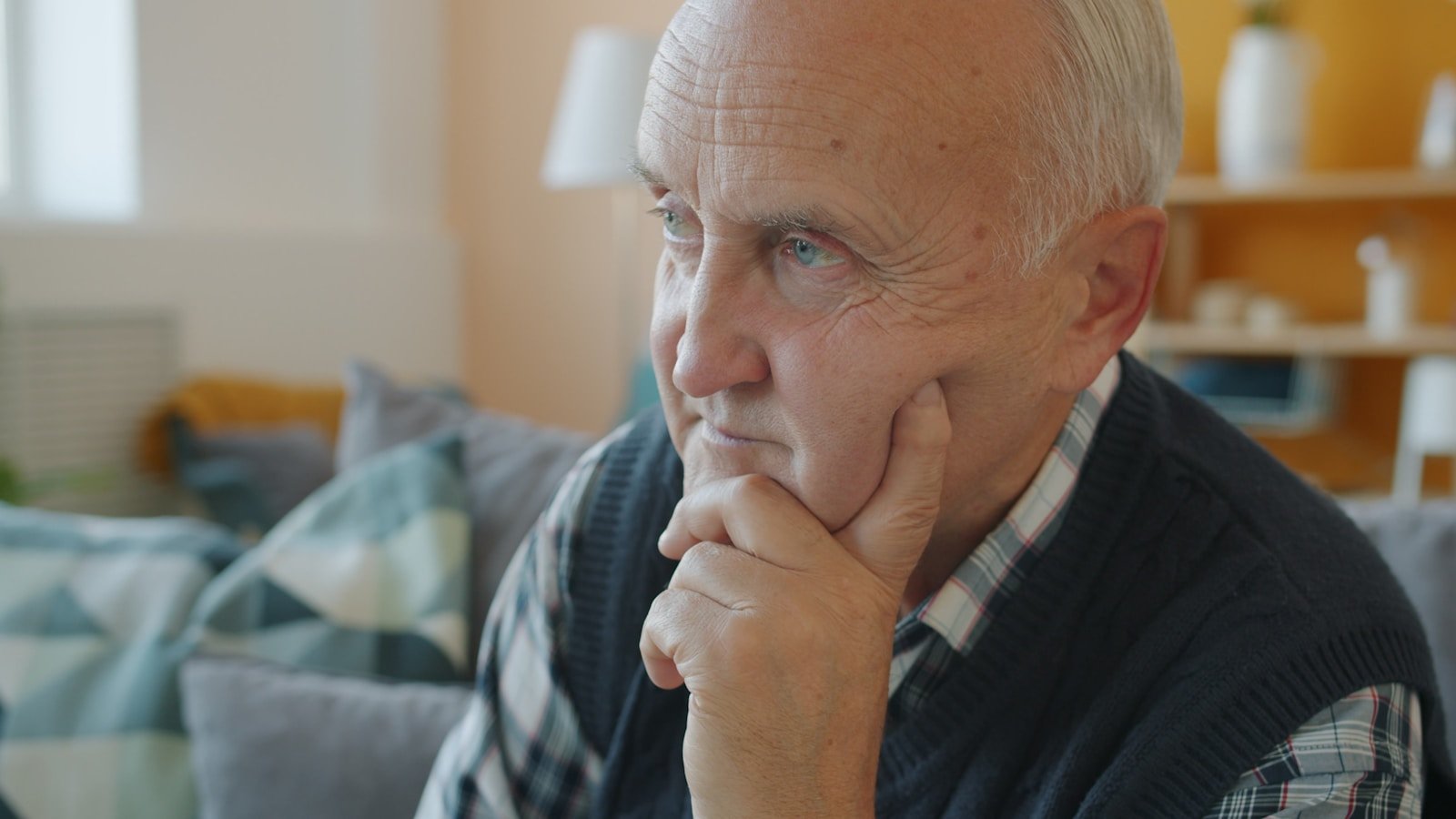 Elderly man with hand on chin, deep in thought.