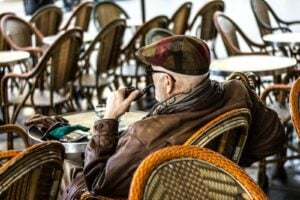 man smoking pipe alone among many chairs