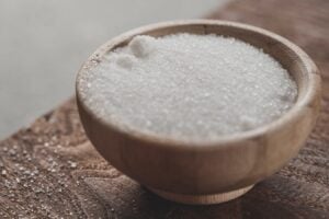 a wooden bowl filled with sugar on top of a wooden table